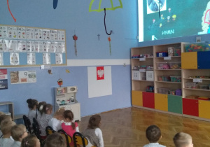 Dzieci oglądają prezentację multimedialną o symbolach narodowych.